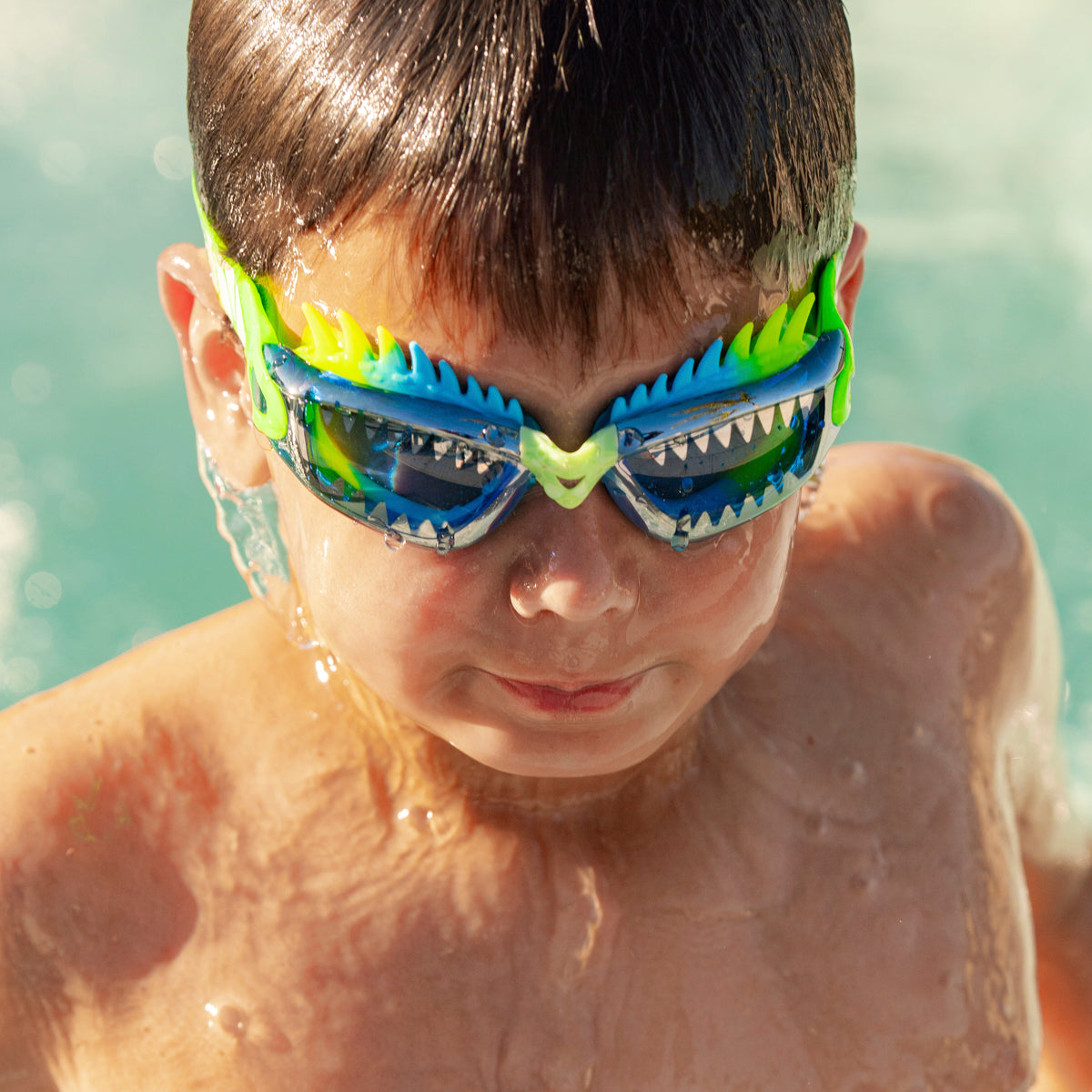boy swimming getting out of pool wearing draco the dragon kids' swim goggles in sea dragon green showing silicone spiked gasket and sharp teeth printed lens