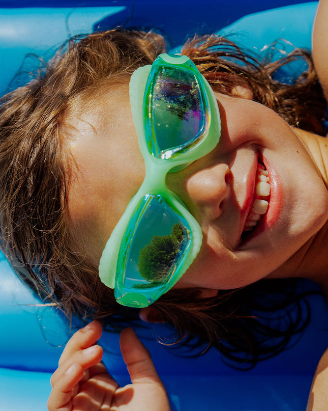 explore the pool kids swim goggles in sea green lifestyle of boy wearing sea green swim goggles on pool float