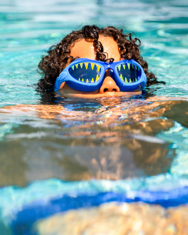 boy swimming wearing megamouth kids' swim goggles in riptide royal showing shark teeth screen printed on the lens