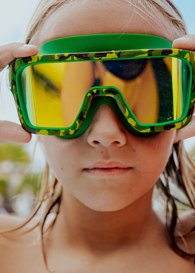 boy poolside wearing special ops kids' swim goggles in guerilla green showing wide frame swim goggles and a green camo printed frame