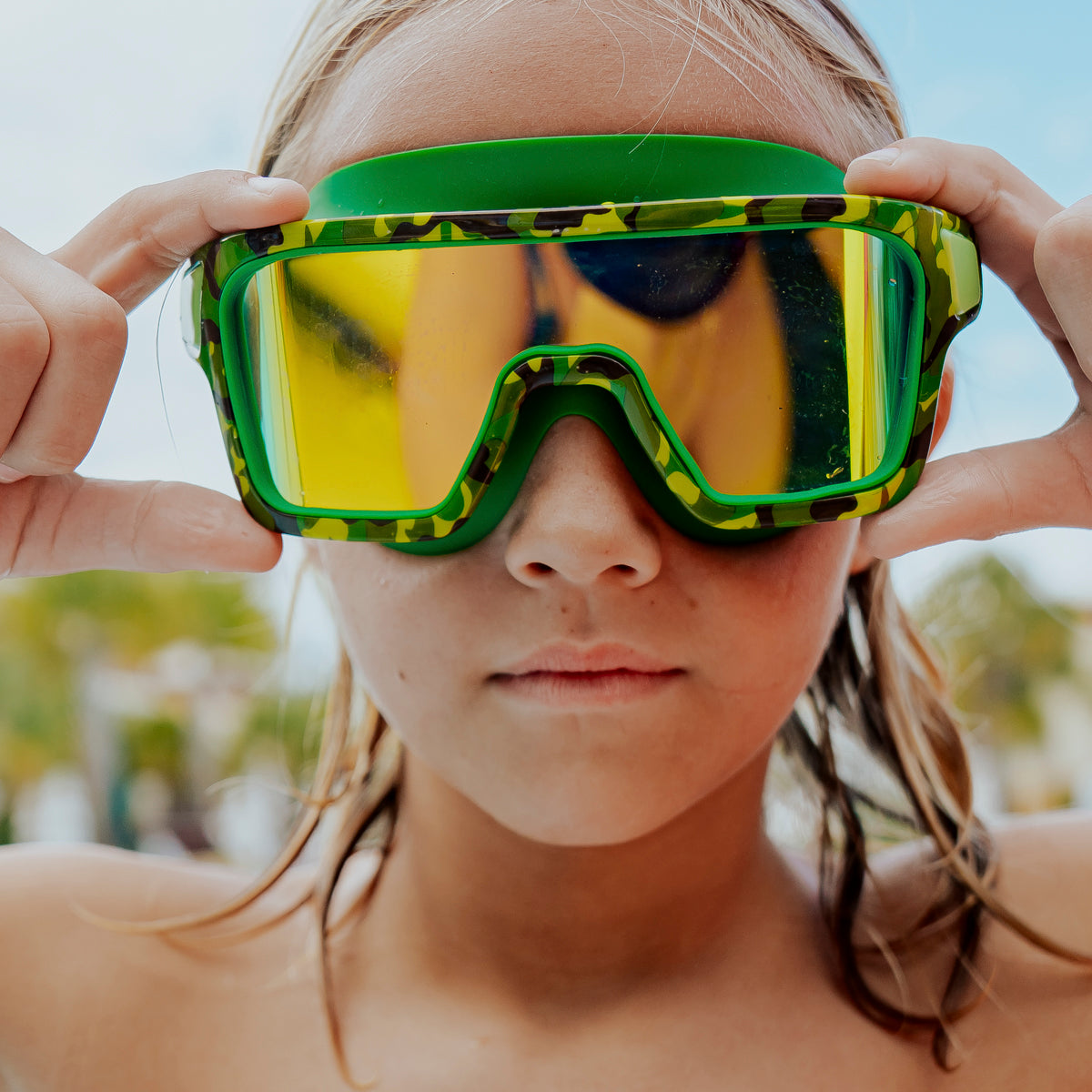 boy poolside wearing special ops kids' swim goggles in guerilla green showing wide frame swim goggles and a green camo printed frame