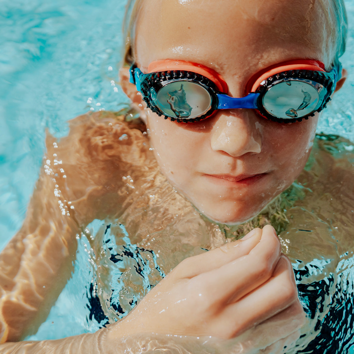 child swimming wearing turbo drive kids' swim goggles in race car red showing car tire tread frame and red gasket