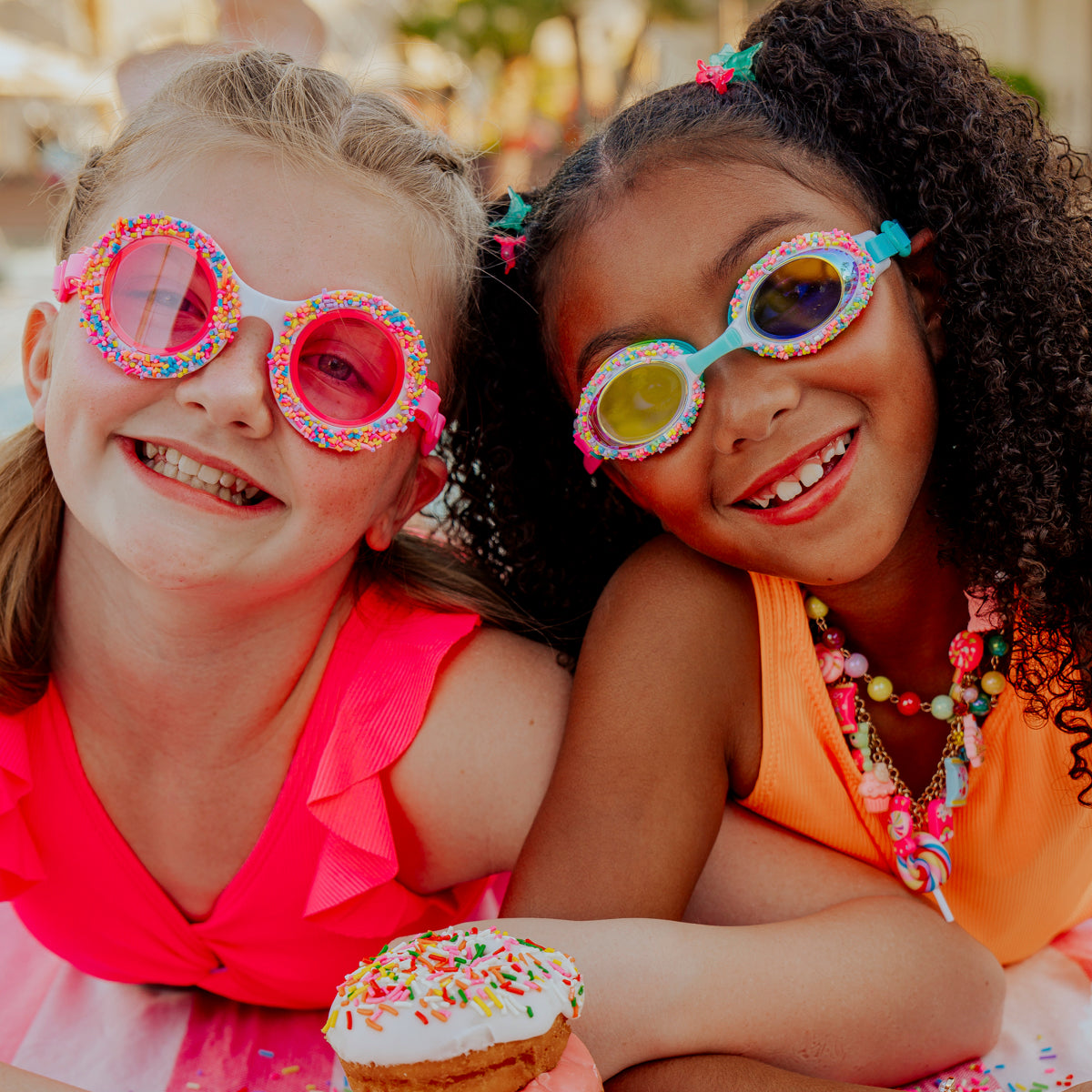 girls laying on beach towel with snacks in donuts 4 u kids' swim goggles and cake pop kids' swim goggles
