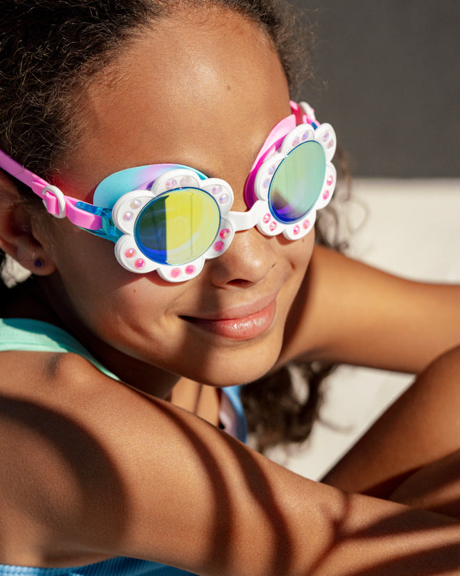 girl smiling wearing dandi flower shaped kids swim goggles in blanche blossom showing petal detail with rhinestones and mirrored lens