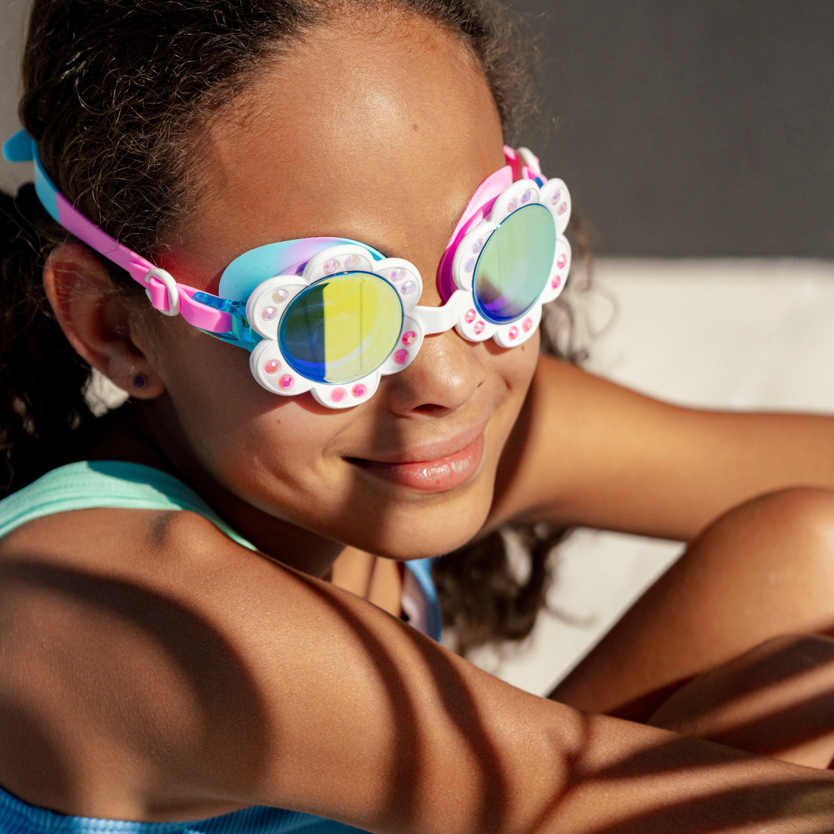 girl smiling wearing dandi flower shaped kids swim goggles in blanche blossom showing petal detail with rhinestones and mirrored lens
