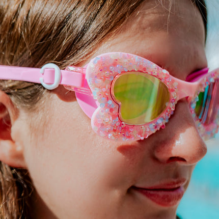 close-up lifestyle of girl in butterfly shaped kids swim goggles in blush butterfly showing crushed rhinestones on the frame