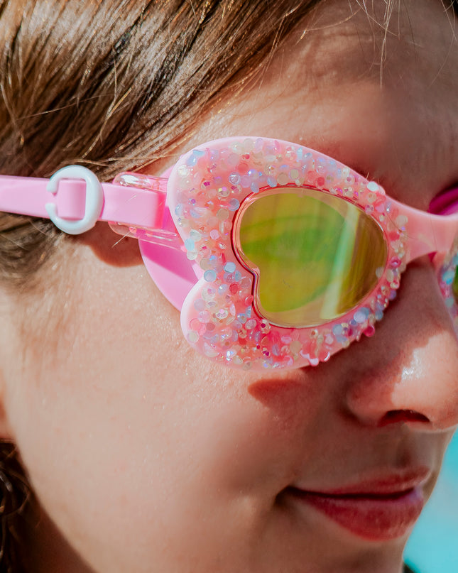 close-up lifestyle of girl in butterfly shaped kids swim goggles in blush butterfly showing crushed rhinestones on the frame