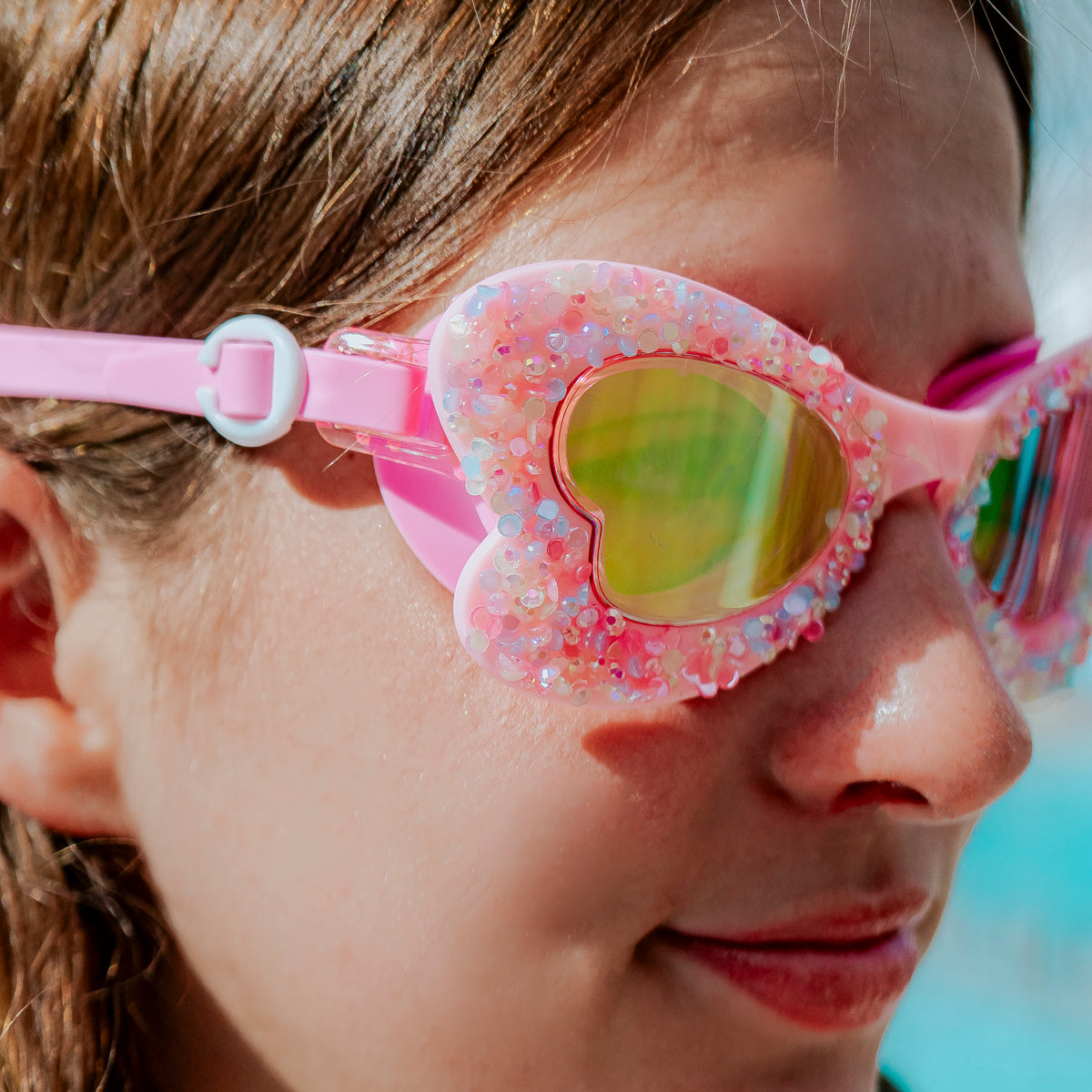 close-up lifestyle of girl in butterfly shaped kids swim goggles in blush butterfly showing crushed rhinestones on the frame