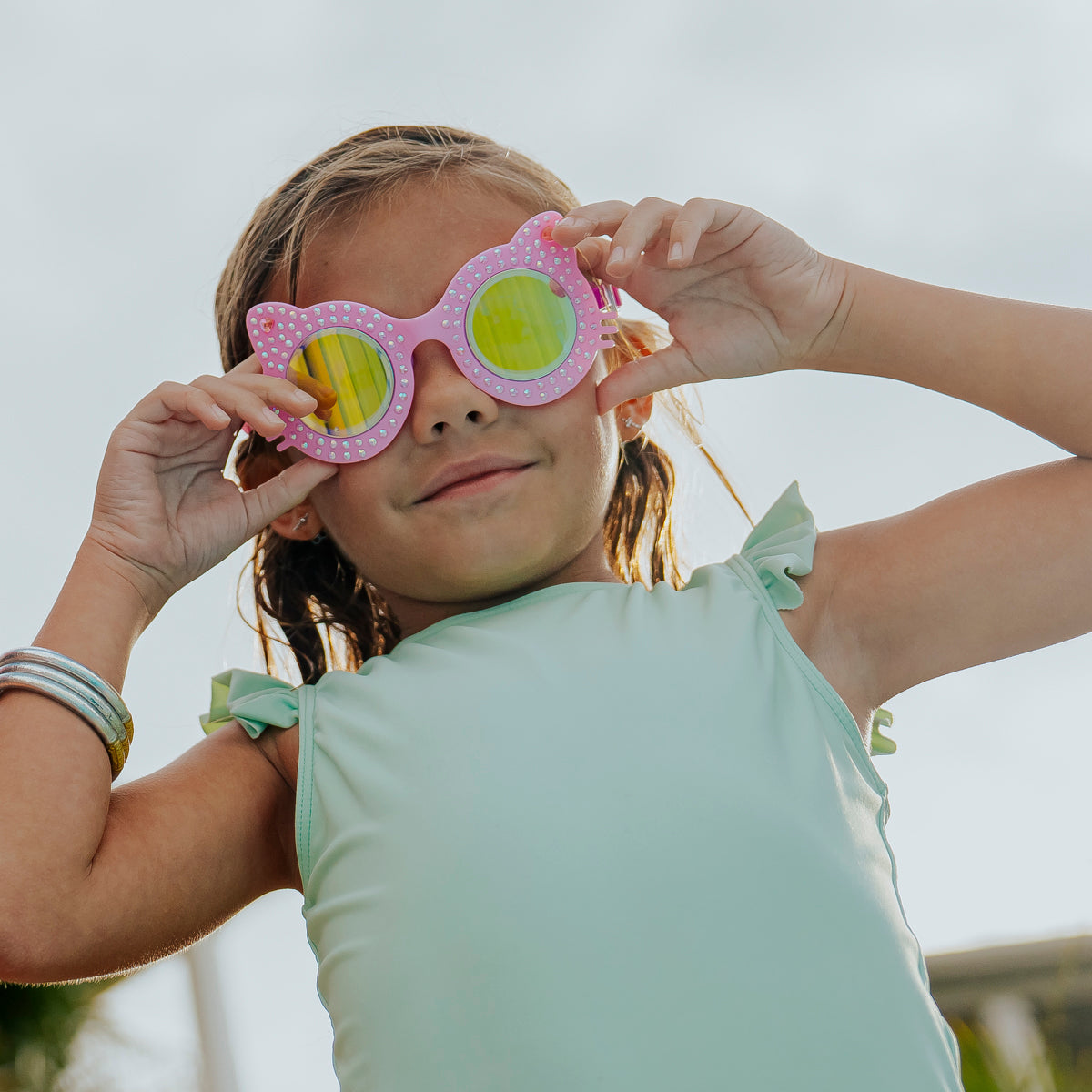 girl smiling looking at camera wearing kitten kids cat-shaped swim goggles in paw print pink showing rhinestone details