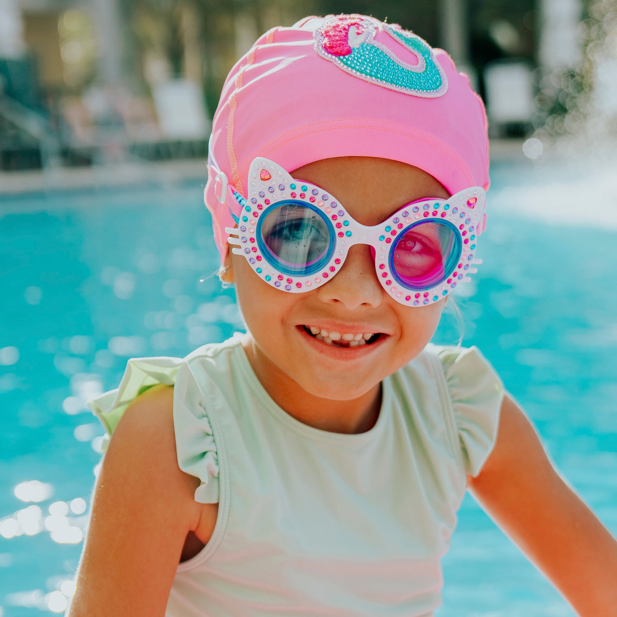 girl smiling in pool wearing kittens kids cat-shaped swim goggles in porcelain paws white showing multi colored rhinestones