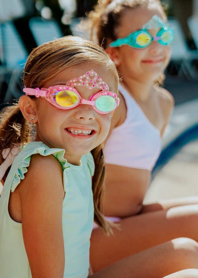 girls sitting poolside smiling wearng royal crown kids' swim goggles showing crown and rhinestone detail