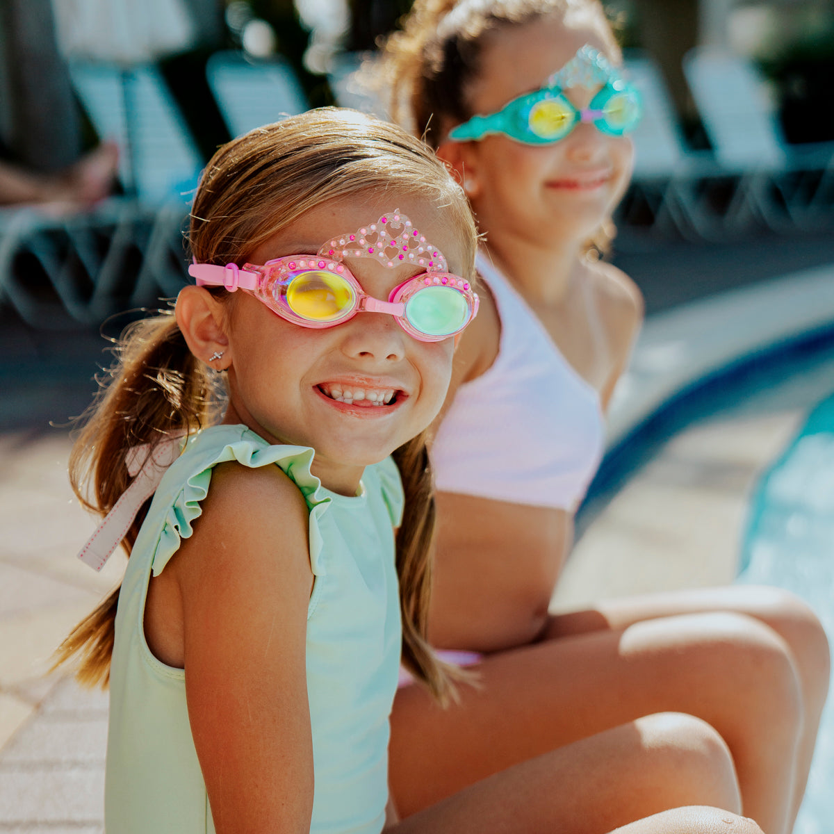 girls sitting poolside smiling wearng royal crown kids' swim goggles showing crown and rhinestone detail