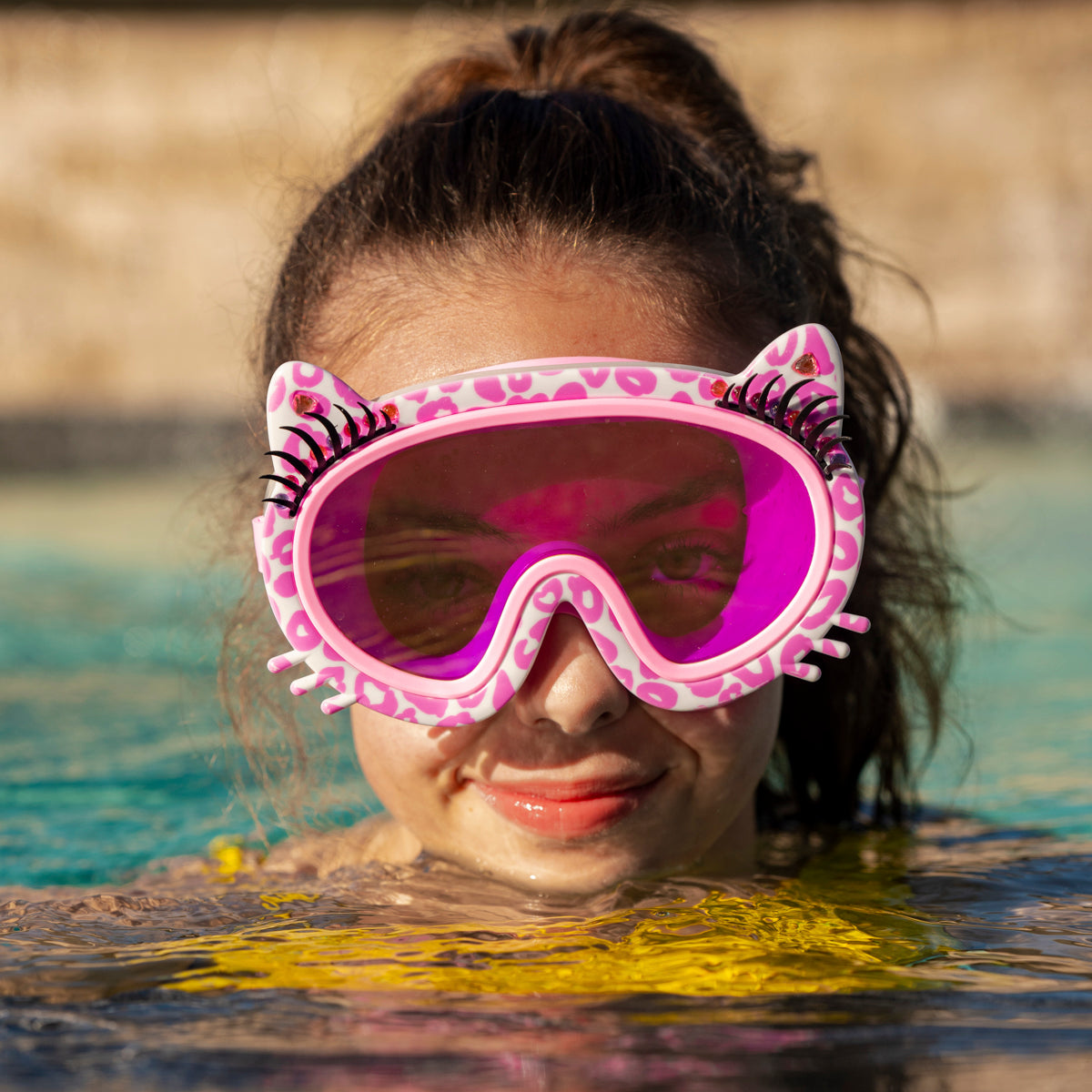 girl swimming wearing meow kids' swim mask in copy cat pink showing pink cheetah printed frame, faux whiskers and eyelashes with rhinestone