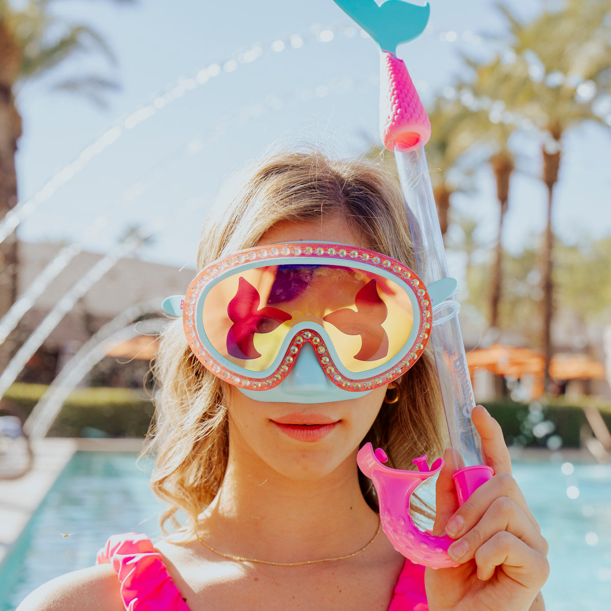 girl at swimming pool wearing blue sea kids' swim mask with nose piece in blue sushi colorway showing reflective translucent mermaid tail print lens on rhinestone glitter frame