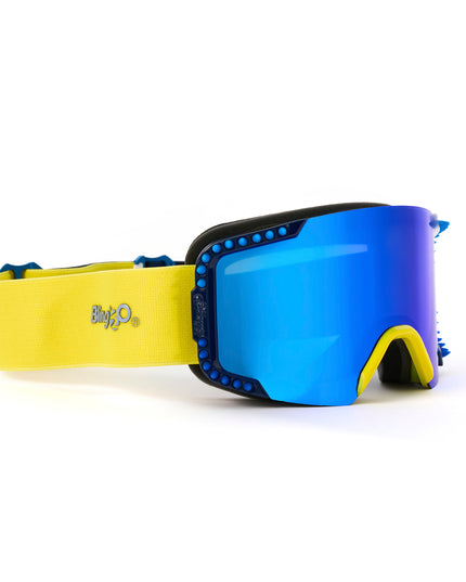 side angled product shot of prism peak kids ski goggles in blue bird which features a blue mirrored lens with blue silicone spikes and a yellow nose piece