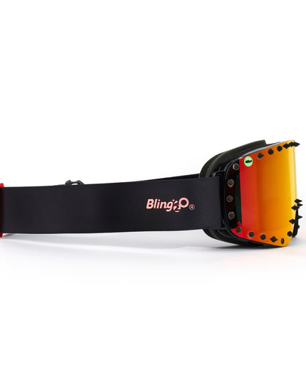 side angle of prism peak kids' ski goggles featuring a red orange mirrored lens with black spikes and a monster eye decal with a black strap and red buckle