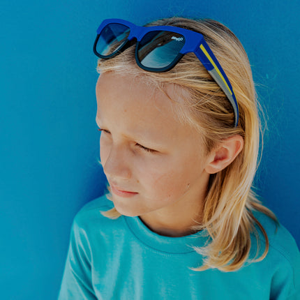 boy wearing firesland kids' sunglasses in royal sunrays on head pushing hair back 