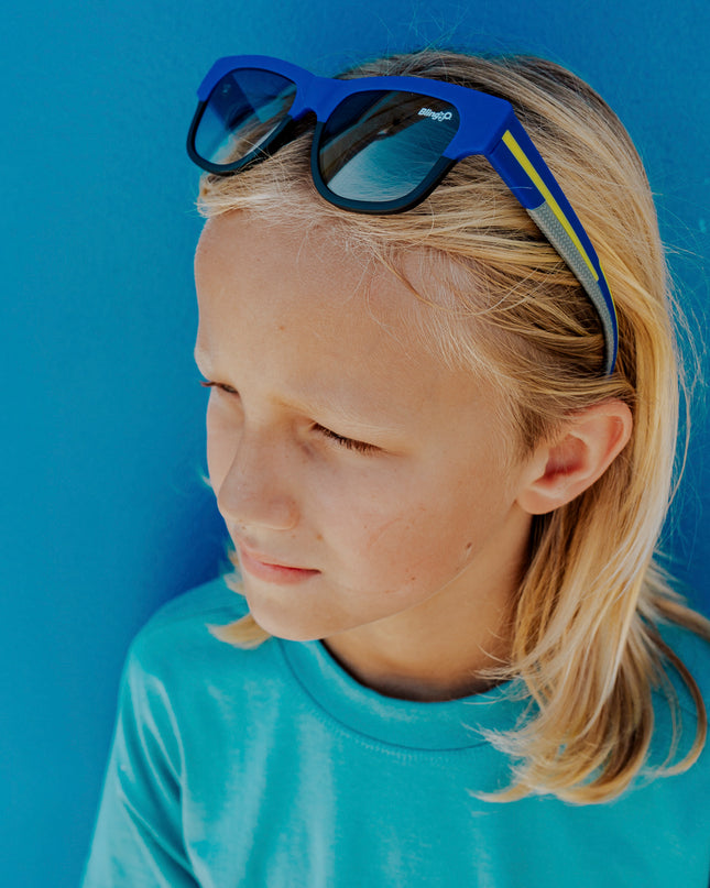 boy wearing firesland kids' sunglasses in royal sunrays on head pushing hair back 