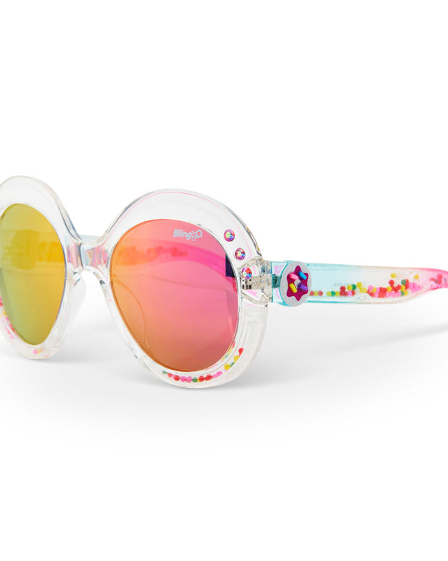 angled view of glass beach kids sunglasses in sprinkle sunrise showing reflective lens, clear large round frame with 3D gumballs in the arm of the sunglass