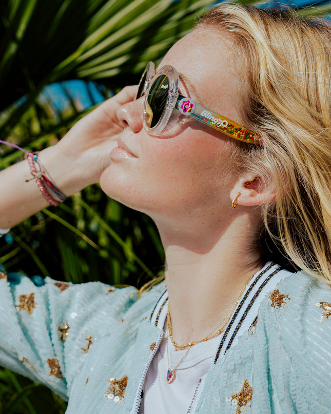 girl posing in sun smiling wearing glass beach kids sunglasses in sprinkle sunrise showing clear large round frame with 3D gumballs in the arm of the sunglass