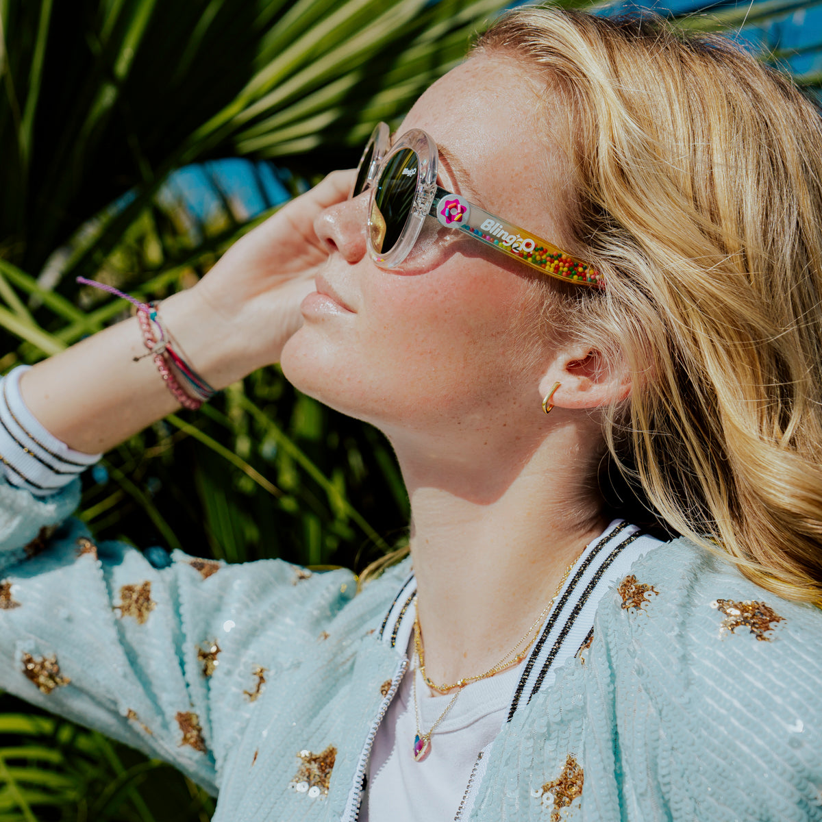 girl posing in sun smiling wearing glass beach kids sunglasses in sprinkle sunrise showing clear large round frame with 3D gumballs in the arm of the sunglass