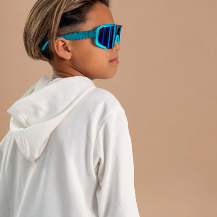kid looking over shoulder posing and wearing gulf shore kids' sunglasses in the color siesta sea