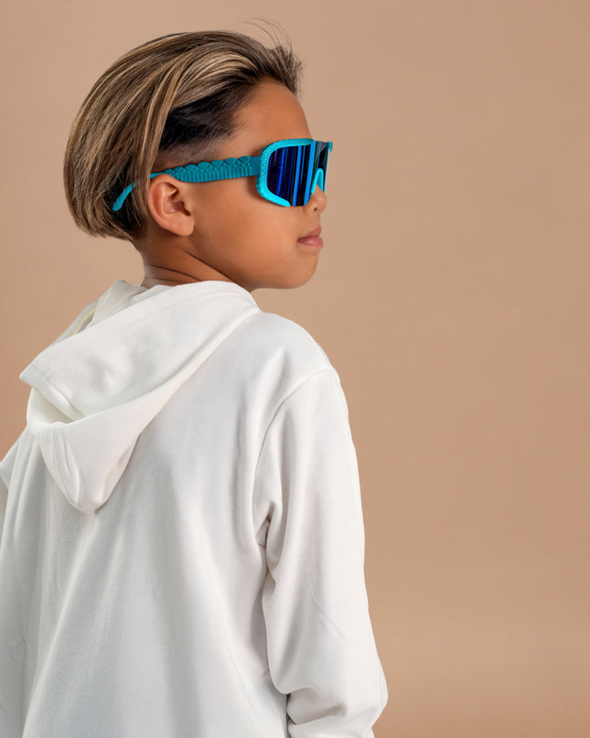 kid looking over shoulder posing and wearing gulf shore kids' sunglasses in the color siesta sea