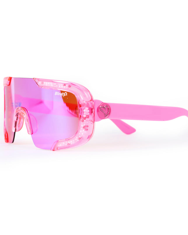 angled product shot of pink sand kids' sunglasses in color sprinkle pink featuring shield frame with 3-d sprinkles in the frame, heart insignia and all pink frame and lens