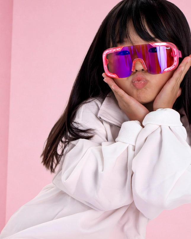 girl posing in pink studio wearing pink sand kids sunglasses in the color sprinkle pink 