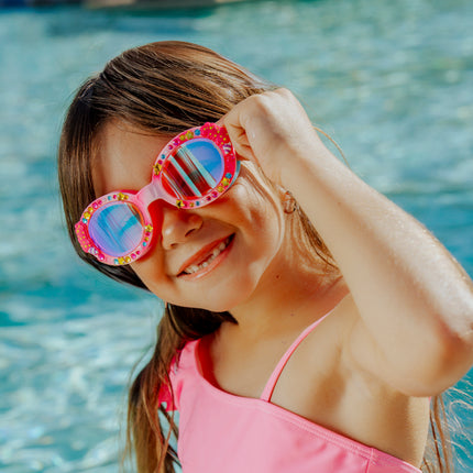lifestyle of girl in front of pool smiling wearing candy carnival kids swim goggles showing rhinestones and cotton candy detail