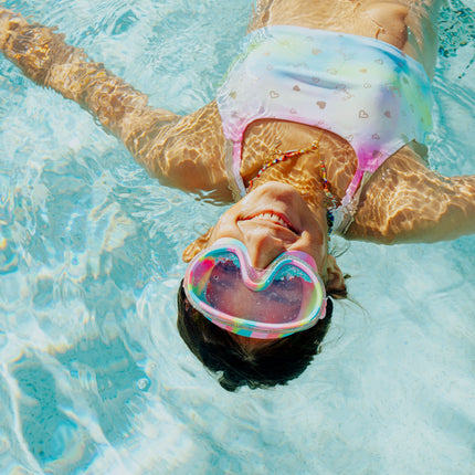lifestyle of girl floating in pool wearing crystal current in sapphire swirl showing turquoise glitter settled at the bottom of the frame