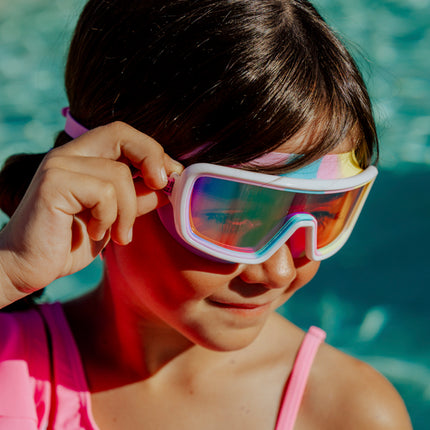 lifestyle of girl in front of swimming pool wearing cyberswim kids' swim goggles in robo rainbow 