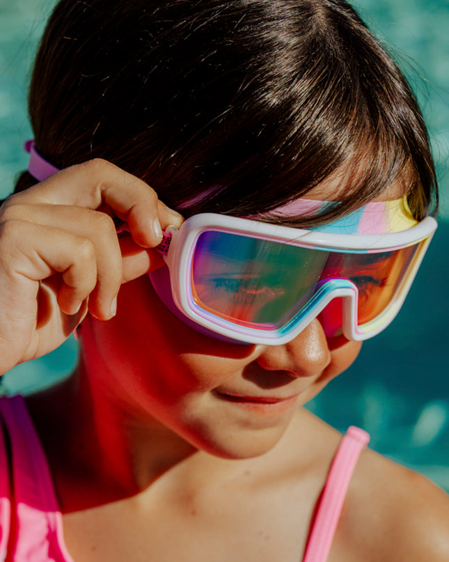 lifestyle of girl in front of swimming pool wearing cyberswim kids' swim goggles in robo rainbow 