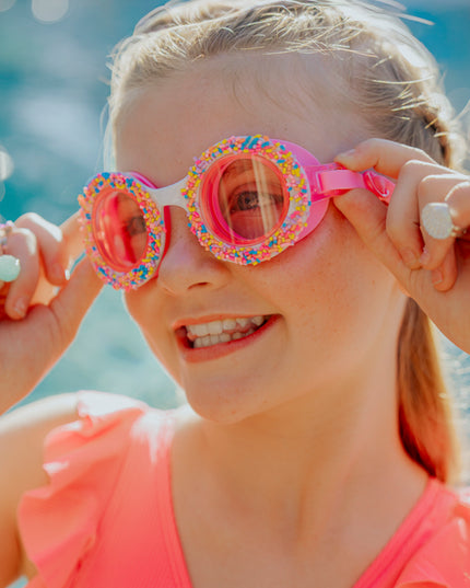Lifestyle of girl wearing donuts 4 u swim goggles in boston creme pink showing sprinkles and pink silicone