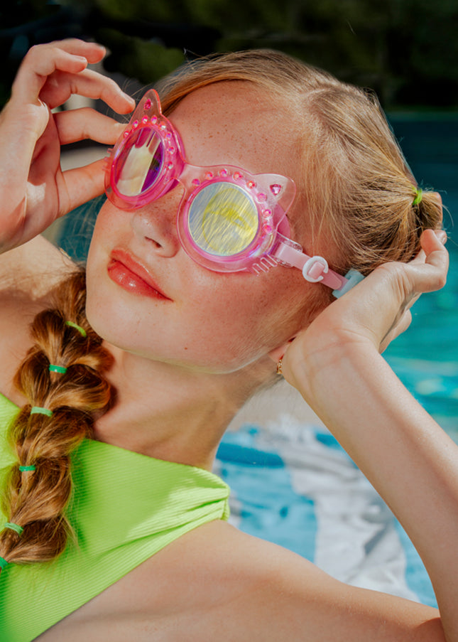lifestyle image of girl poolside wearing frosted feline swim goggles in pink purr showing pink frame and rhinestones