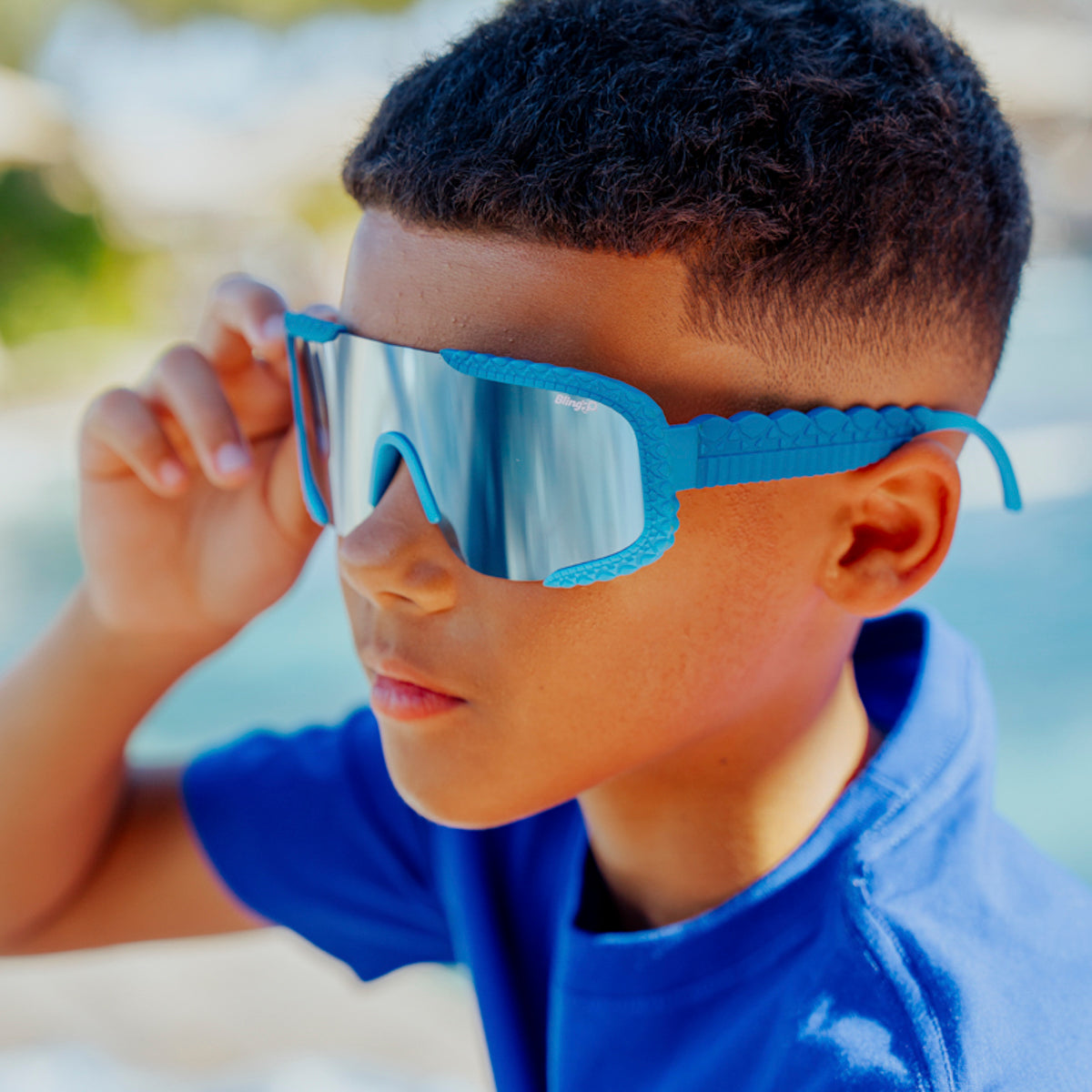 lifestyle of kid wearing gulfshore kids sunglasses in crocodile cobalt blue showing texture on frame and arm