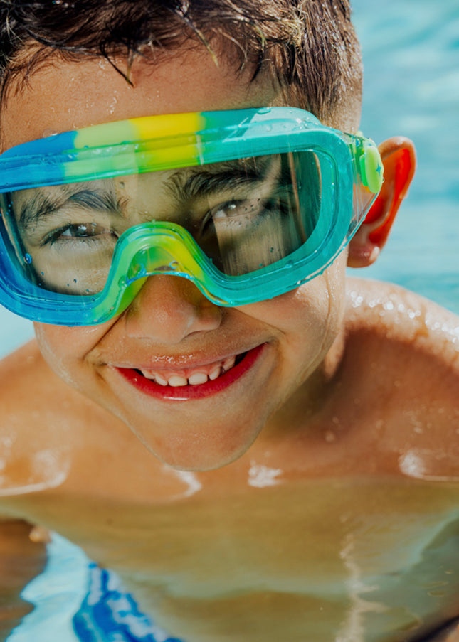 lifestyle of boy in pool swimming wearin hologram swim goggles in cyber green showing frameless lens and swirls of green silicone gasket
