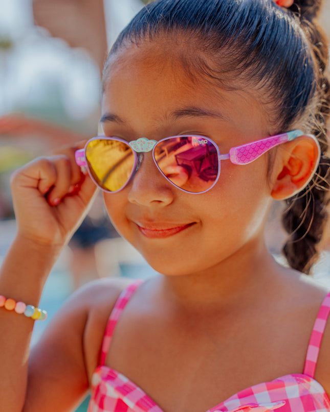 lifestyle of girl smiling adjusting hampton kids sunglasses in suntan turq showing mermaid tail detail on arm and rhinestone nose piece