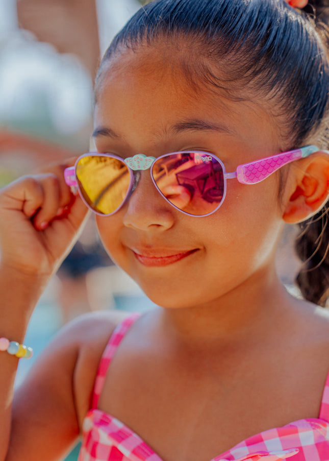 lifestyle of girl smiling adjusting hampton kids sunglasses in suntan turq showing mermaid tail detail on arm and rhinestone nose piece