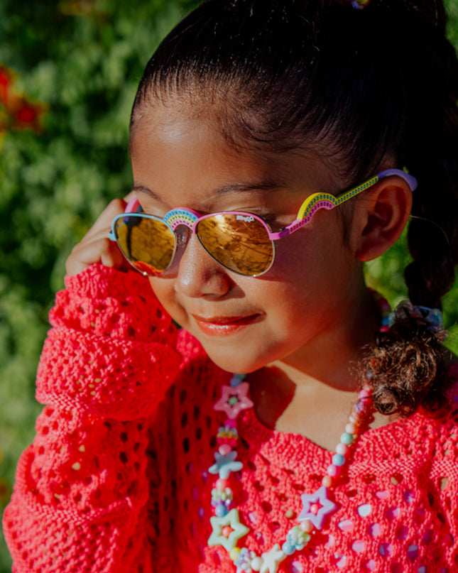 lifestyle of girl posing wearing ibiza kids sunglasses in rising rainbow showing rainbow shaped nose bridge and arm with rhinestones