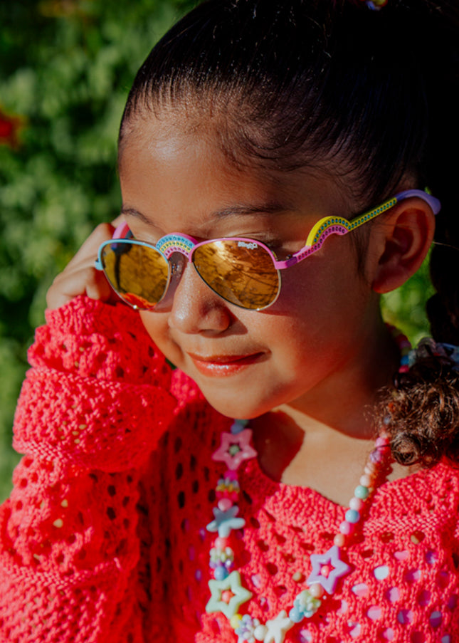lifestyle of girl posing wearing ibiza kids sunglasses in rising rainbow showing rainbow shaped nose bridge and arm with rhinestones
