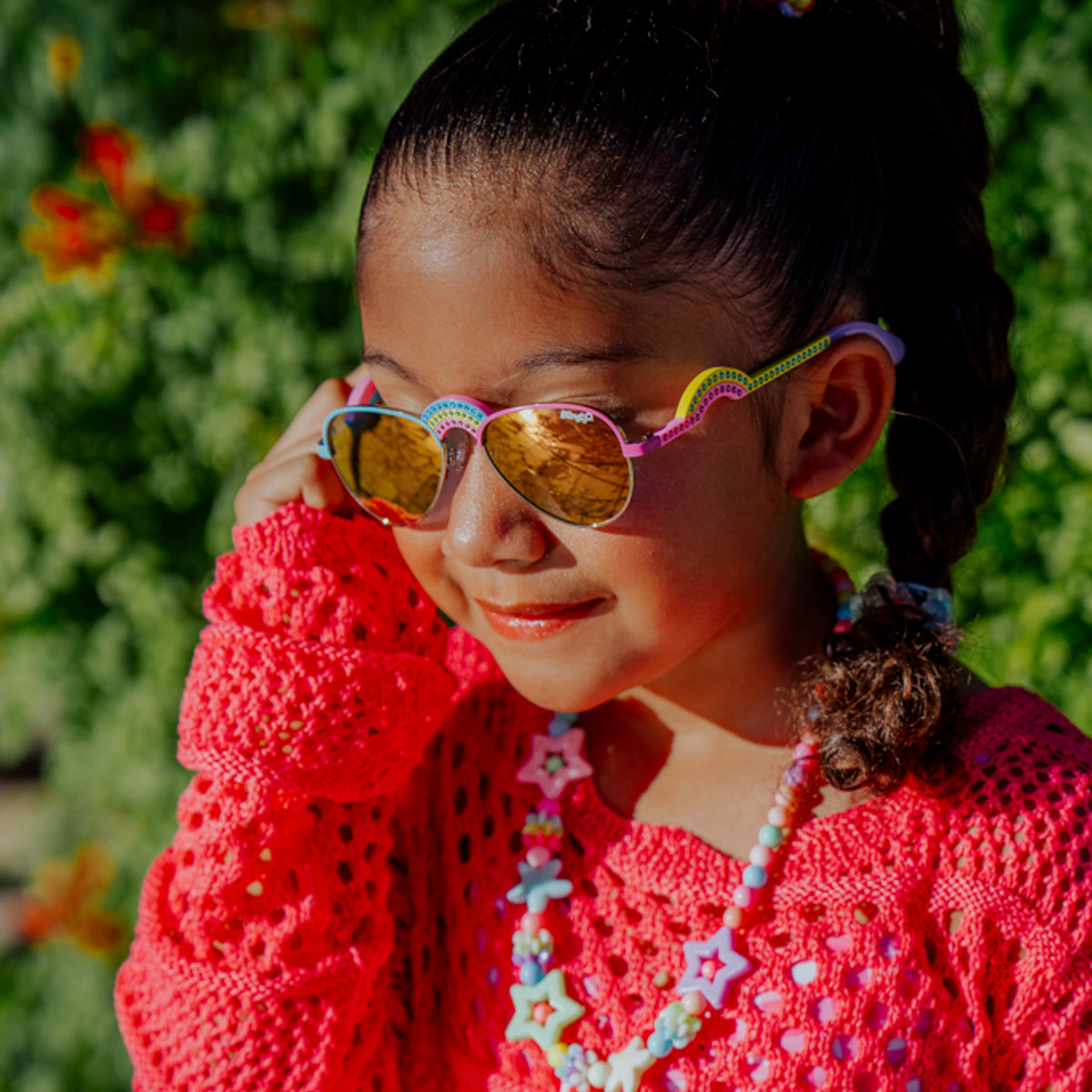 lifestyle of girl posing wearing ibiza kids sunglasses in rising rainbow showing rainbow shaped nose bridge and arm with rhinestones