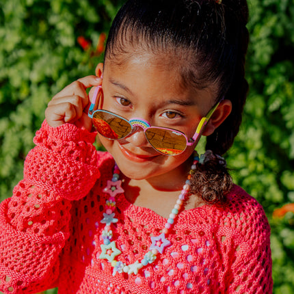 lifestyle of girl posing wearing ibiza kids sunglasses in rising rainbow showing rainbow shaped nose bridge and arm with rhinestones