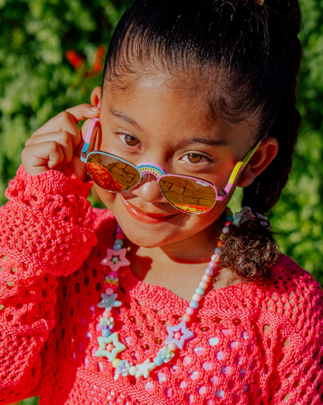 lifestyle of girl posing wearing ibiza kids sunglasses in rising rainbow showing rainbow shaped nose bridge and arm with rhinestones