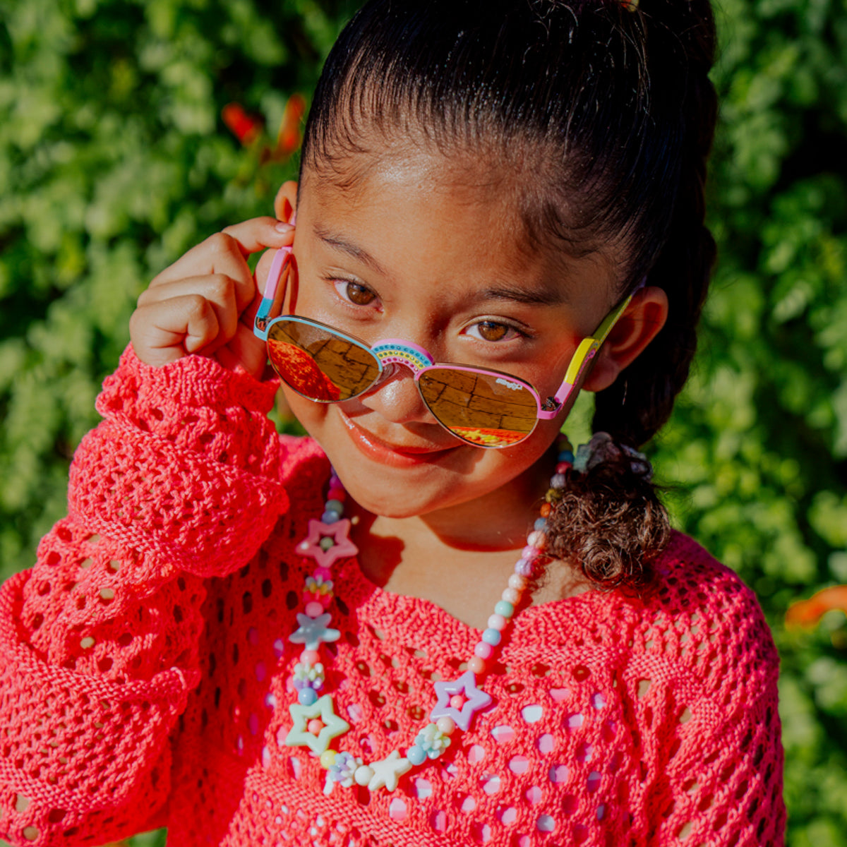 lifestyle of girl posing wearing ibiza kids sunglasses in rising rainbow showing rainbow shaped nose bridge and arm with rhinestones