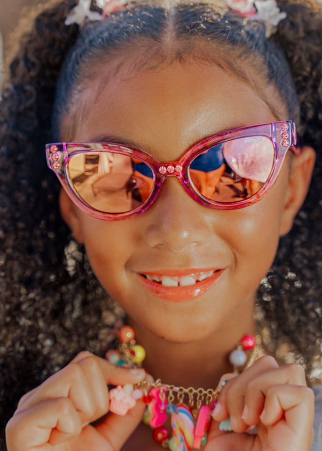 lifestyle of girl wearing malibu kids sunglasses in misty magenta showing purple frame and rhinestones