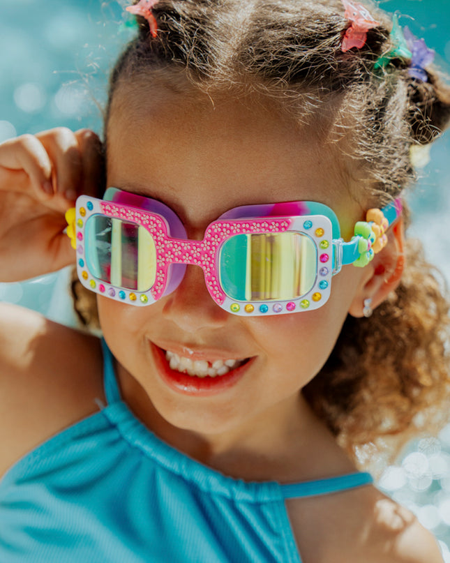 Lifestyle of 4 year old girl smiling wearing Pretty Girl Poppy in Petal Pop Pink kids' swim goggles 