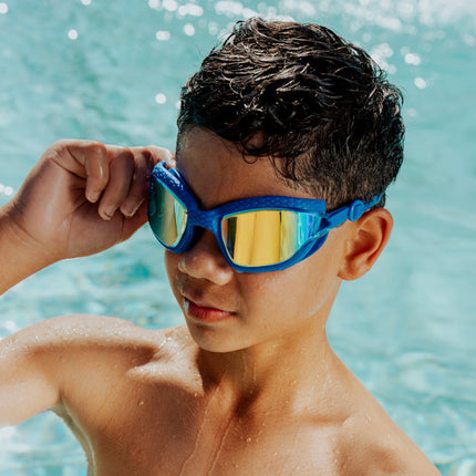 boy wearing standing in front of pool wearing streamline silicone goggles showing reflective lens and textured gasket