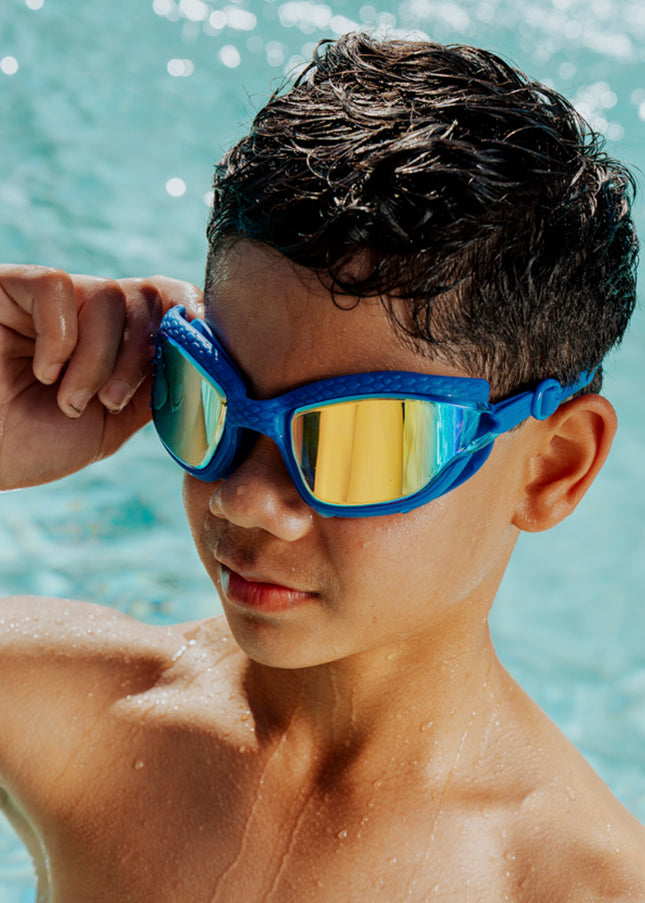boy wearing standing in front of pool wearing streamline silicone goggles showing reflective lens and textured gasket