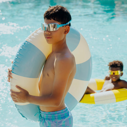 junior boy standing poolside wearing velocity swim goggles in wave blue showing frameless lens and blue silicone strap